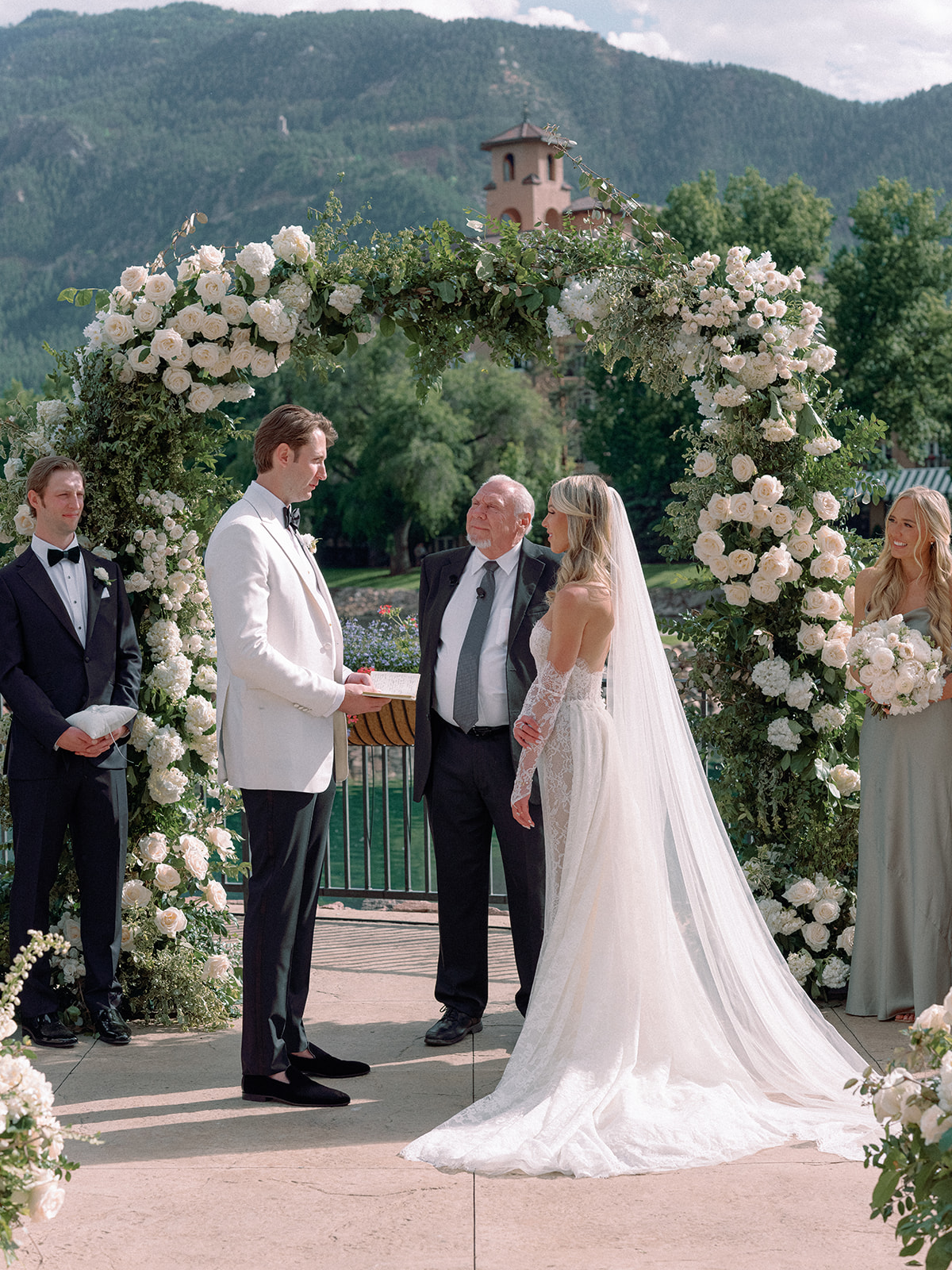 A bride and groom saying 'I do' underneath a lush floral arch at The Broadmoor in Colorado.