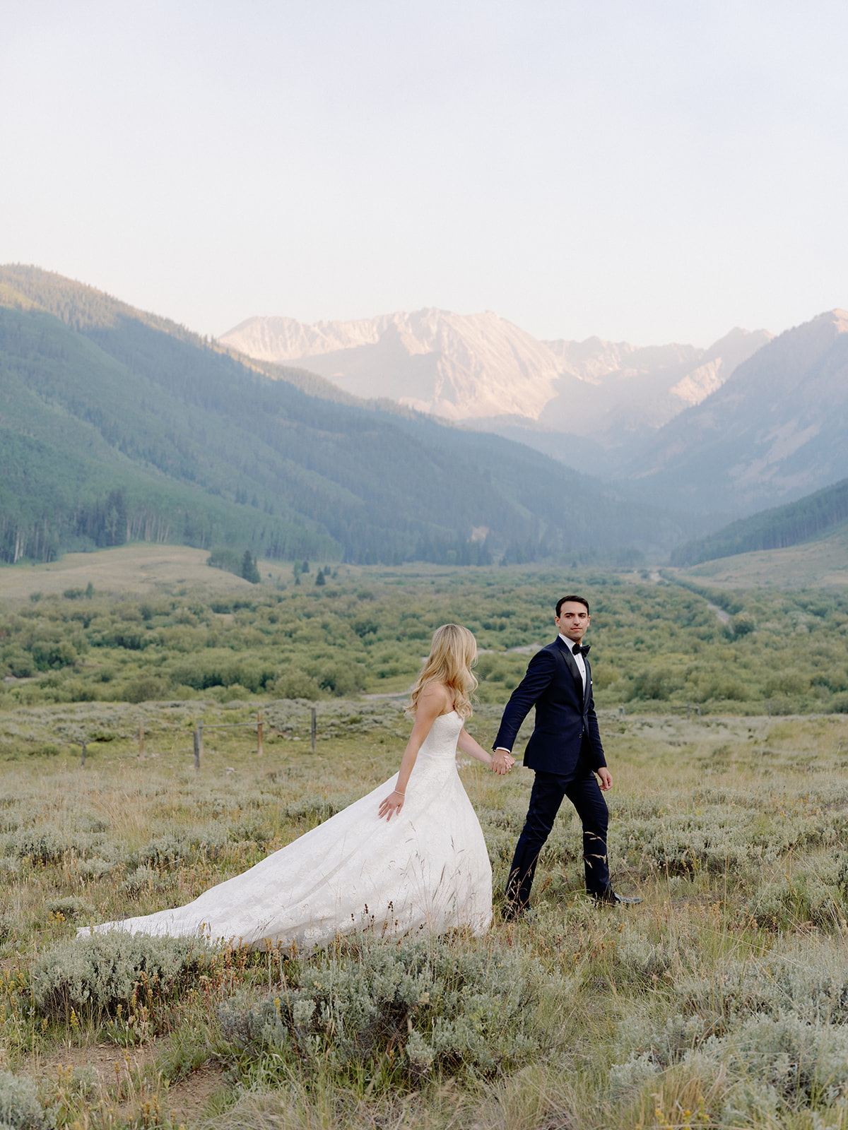 A bride and groom posing for portraits in front of the Colorado mountains.