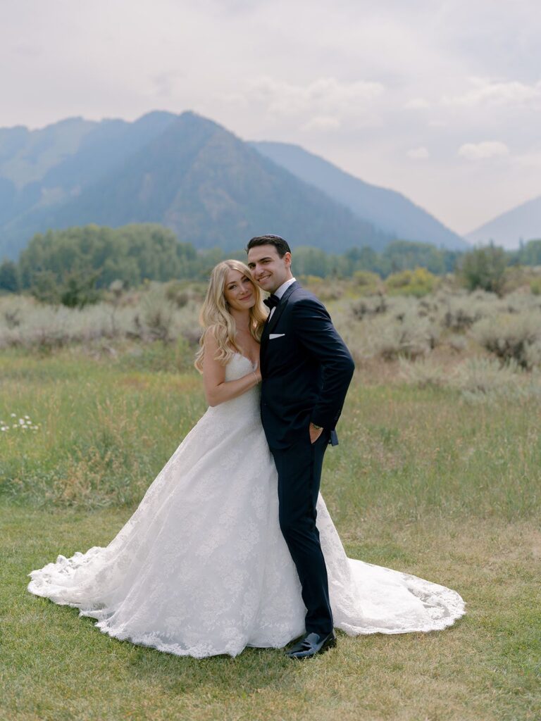 Pine Creek Cookhouse bride and groom posing with mountain range in the background